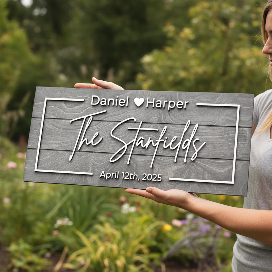 Family established sign reading Daniel and Harper, The Stanfields, April 12th 2025 in raised white letters on a grey board, held in a garden.