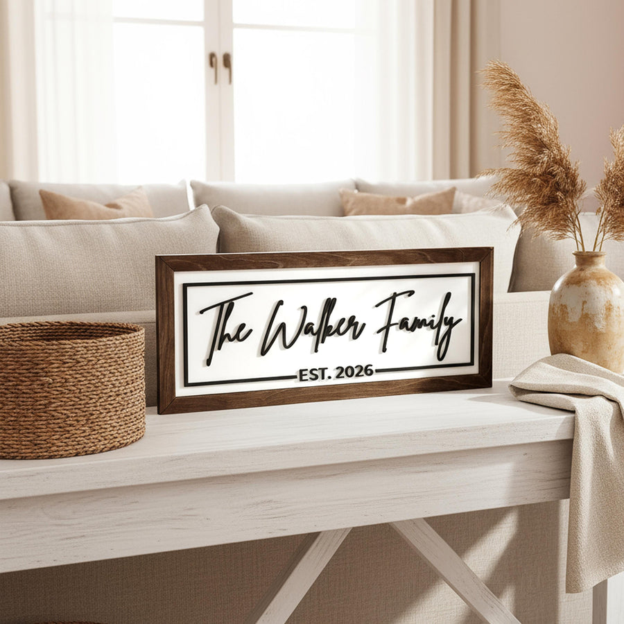 The Walker Family Est. 2026 sign in a Jacobean wood frame on a white console table in front of a linen sofa.