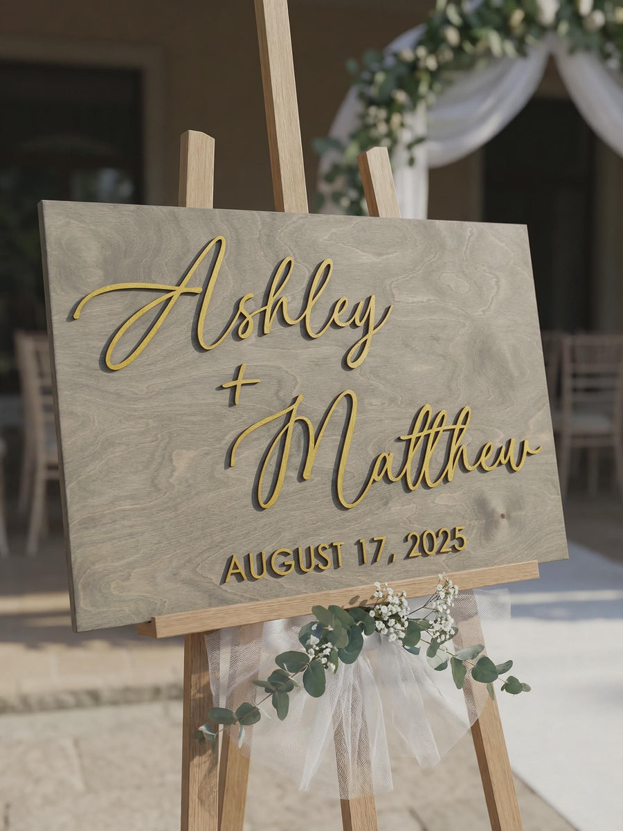 Rustic personalized wedding guestbook sign on an easel during cocktail hour, featuring large raised 3D names, custom date, white handwritten messages, and a matching please sign our guestbook sign on a nearby table.