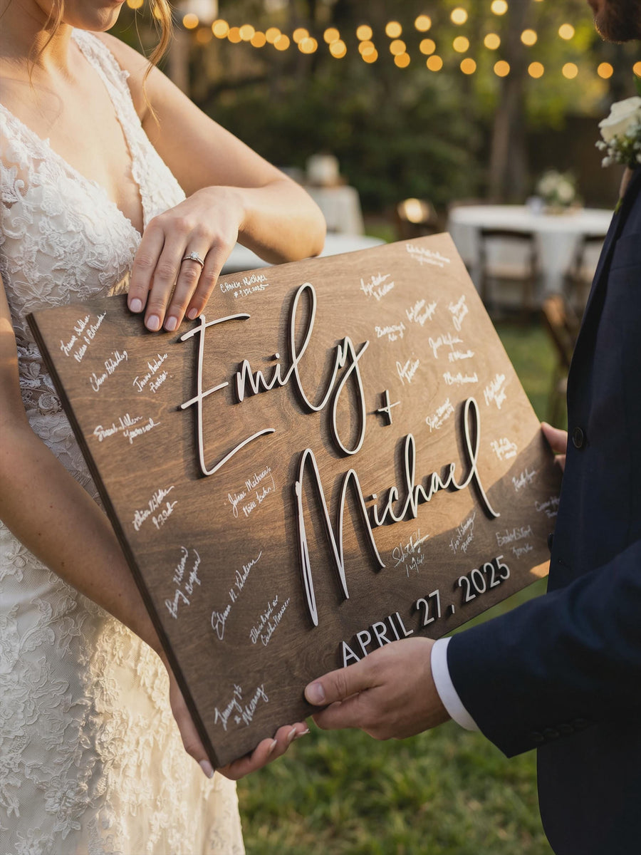 Bride and groom holding personalized wooden wedding guest book alternative, rustic 3D last name sign with custom wedding date and handwritten guest signatures at outdoor reception.