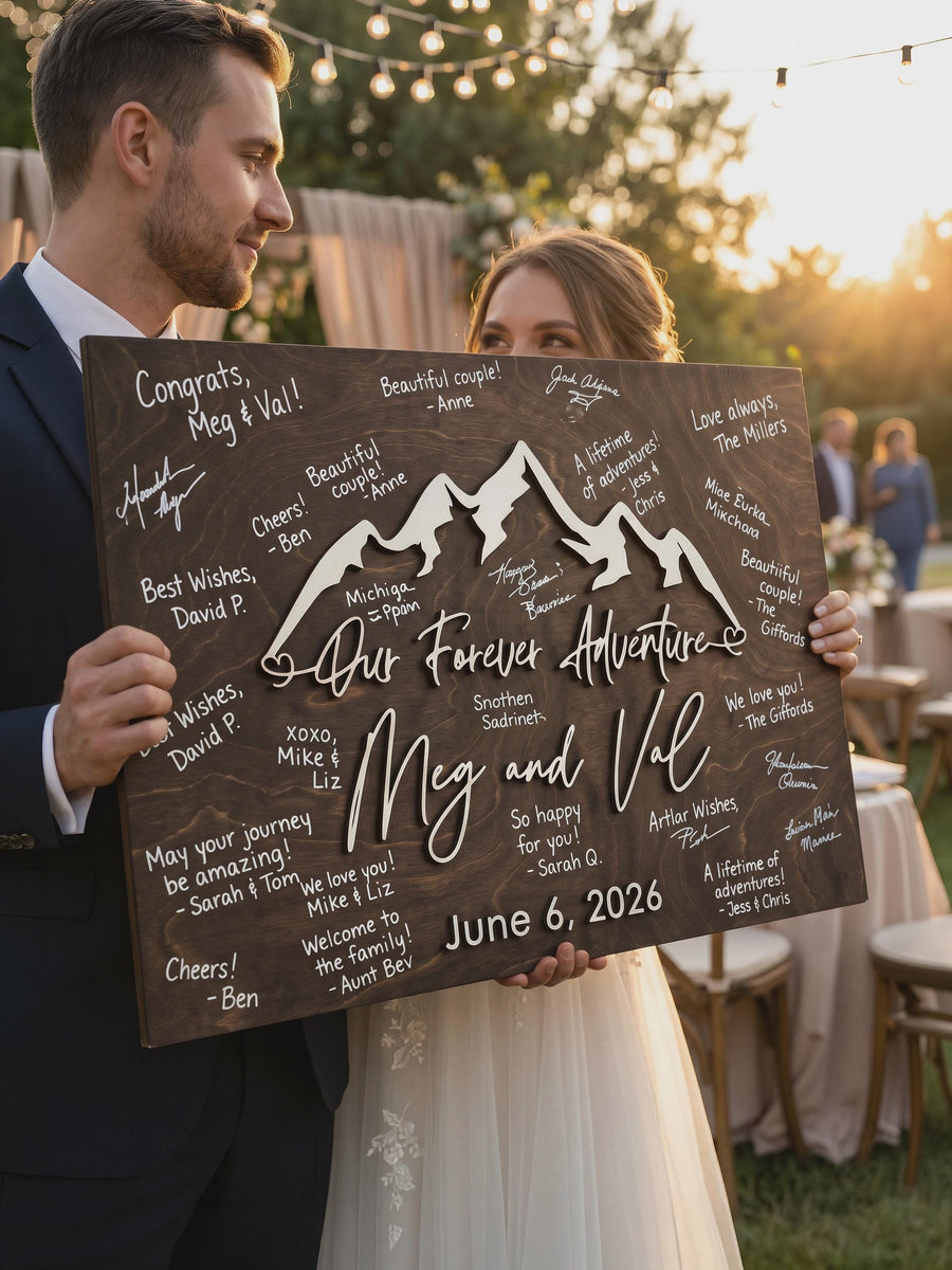 Bride and groom holding the signed Our Forever Adventure mountain guest book sign in Jacobean stain.