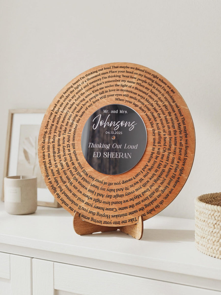 Wooden song record with engraved lyrics in a spiral and a dark mirror center with white lettering, standing on its wooden display stand