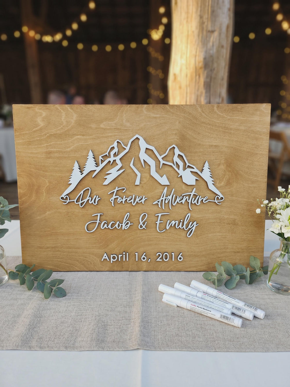 Adventure-themed forest mountain guest book sign with the couple's names.