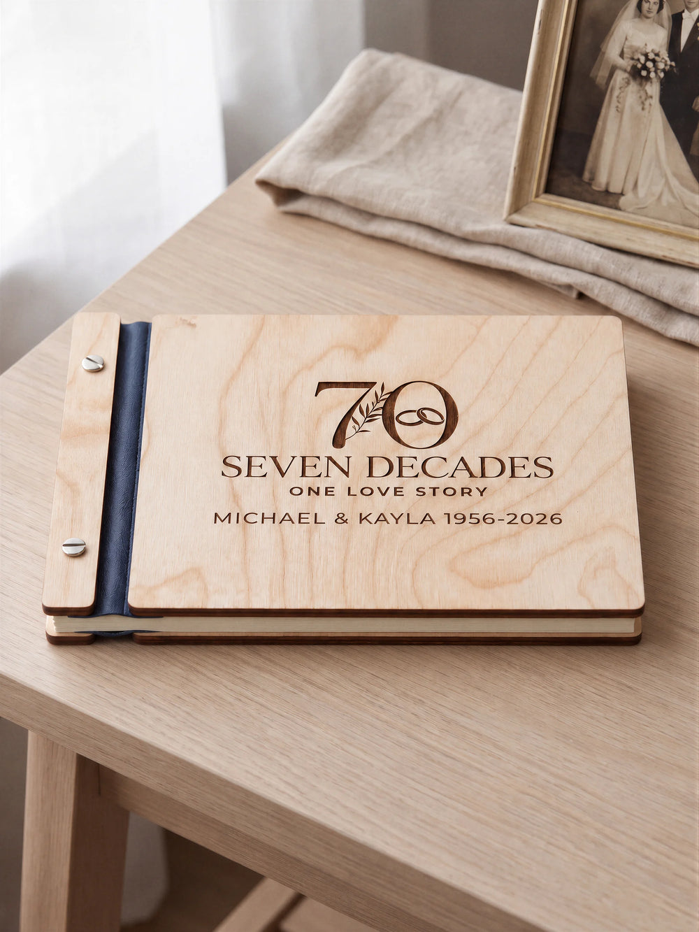 Natural wooden photo album with dark brown laser engraving of a large 70 with a botanical sprig and interlocking wedding rings. The album rests on a light wooden table with navy blue binding and silver screws.