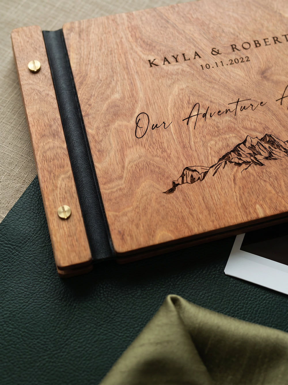 Close-up of the Hazelnut wood Our Adventure Awaits cover, the black vegan leather spine and gold screw posts