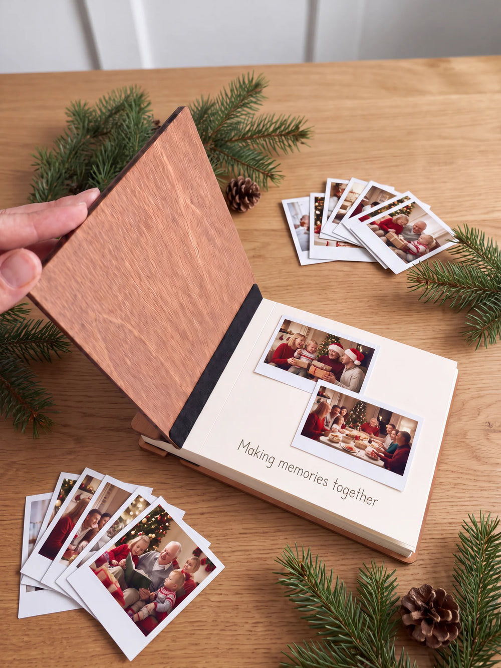 A hand lifts the Hazelnut album’s front cover, revealing a flat black inner fabric strip and a cream page arranged with instant photographs and a handwritten memory.