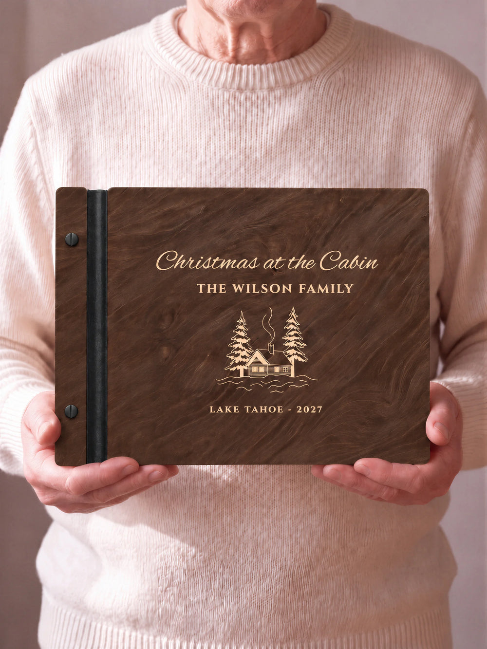 A close view of the dark brown Jacobean album and its cream laser-engraved Christmas at the Cabin design, with black binding and matte black screws.
