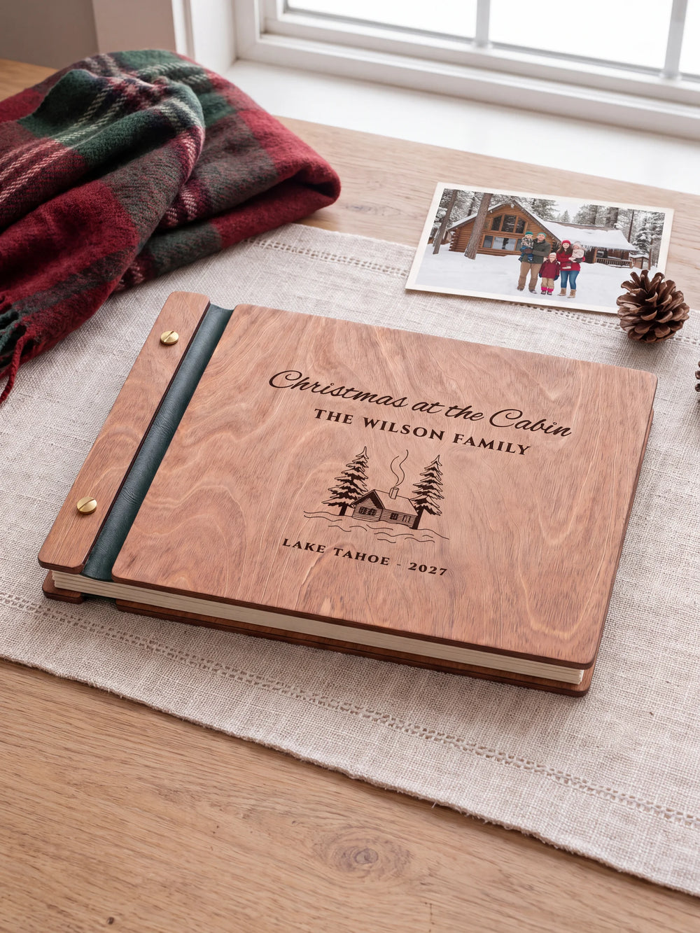 The full Hazelnut Christmas at the Cabin album cover is shown close up. Brown engraved artwork, personalized wording, the narrow binding and gold screws are visible.