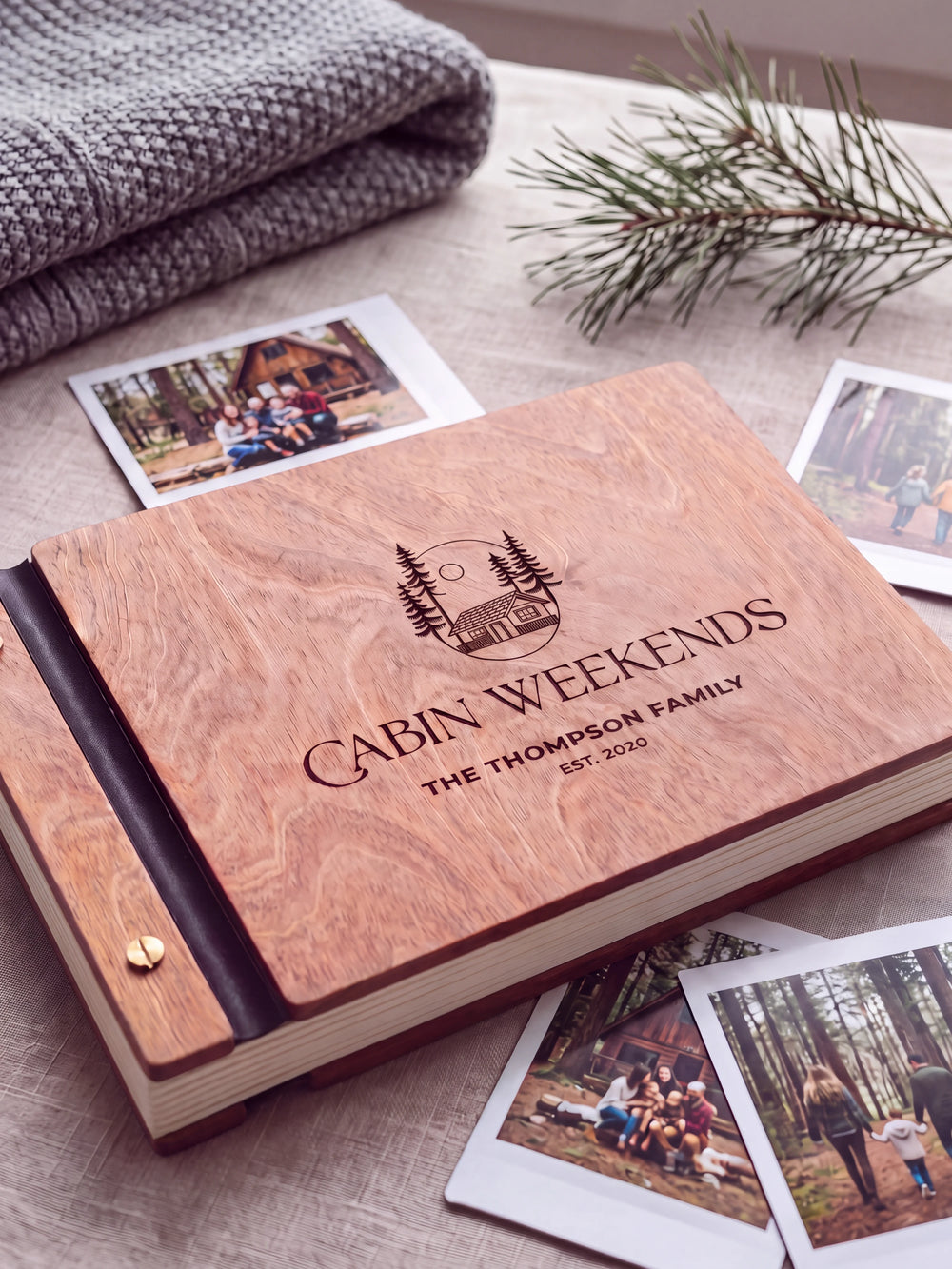 Close-up of a woodland cabin and pine trees engraved in dark brown on the Hazelnut wooden cover, showing the fine artwork and surrounding wood grain.