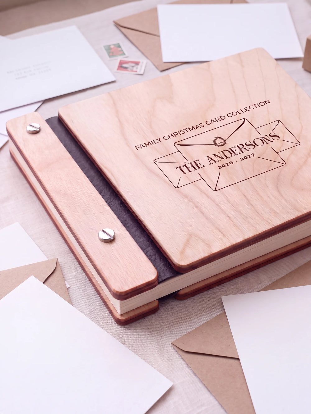 Close view of a Natural wood album with brown engraving, black binding and silver screw heads. The cream page edges and divided wooden cover construction are visible.