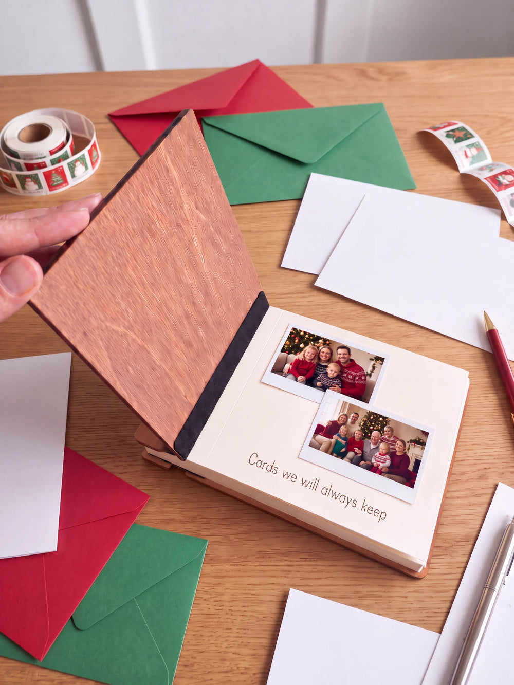 A hand lifts the Hazelnut album’s front cover, revealing a flat black inner fabric strip and a cream page arranged with instant photographs and a handwritten memory.