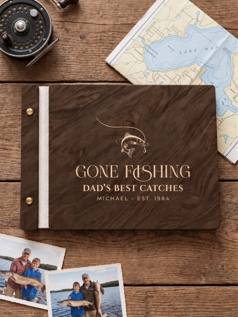 Jacobean wooden album with cream laser engraving of hooked fish and curved fishing line. The full personalized cover rests on a styled surface, with ivory binding and gold screws.