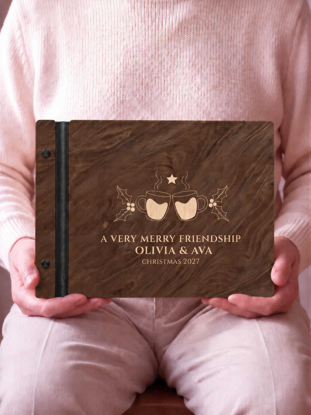 A close view of the dark brown Jacobean album and its cream laser-engraved A VERY MERRY FRIENDSHIP design, with black binding and matte black screws.