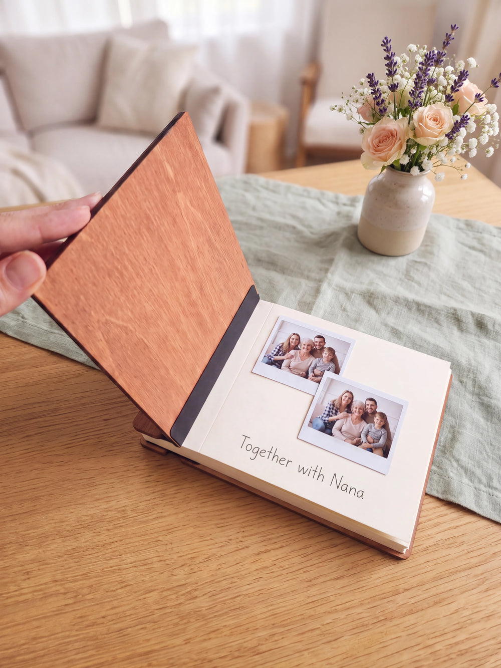 The Hazelnut Grandma's Favorite Memories photo book open on a table with instant photos and a short handwritten note on a cream page; the black hinge strip is visible