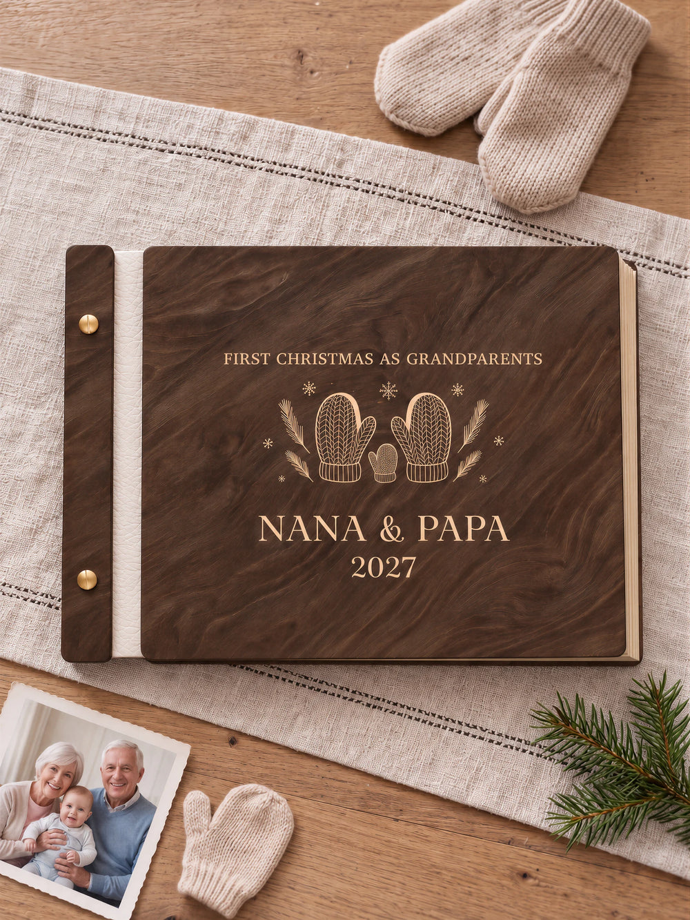 Jacobean wooden album with cream laser engraving of two knitted mittens and a tiny mitten. The full personalized cover rests on a styled surface, with ivory binding and gold screws.