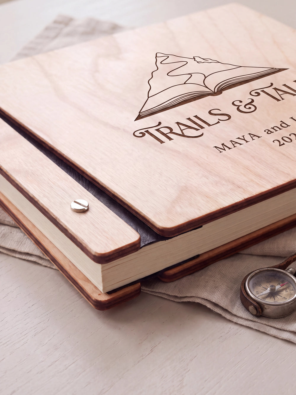 Close-up of the Natural wooden album binding: a polished silver slotted screw, black flexible hinge, separate wooden cover pieces and cream page edges.