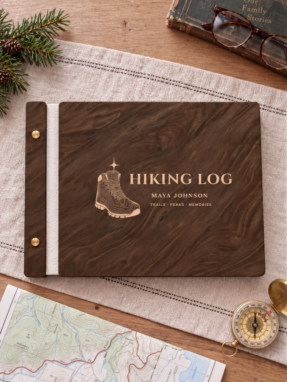 Jacobean wooden album with cream laser engraving of hiking boot with topographic contours and star. The full personalized cover rests on a styled surface, with ivory binding and gold screws.