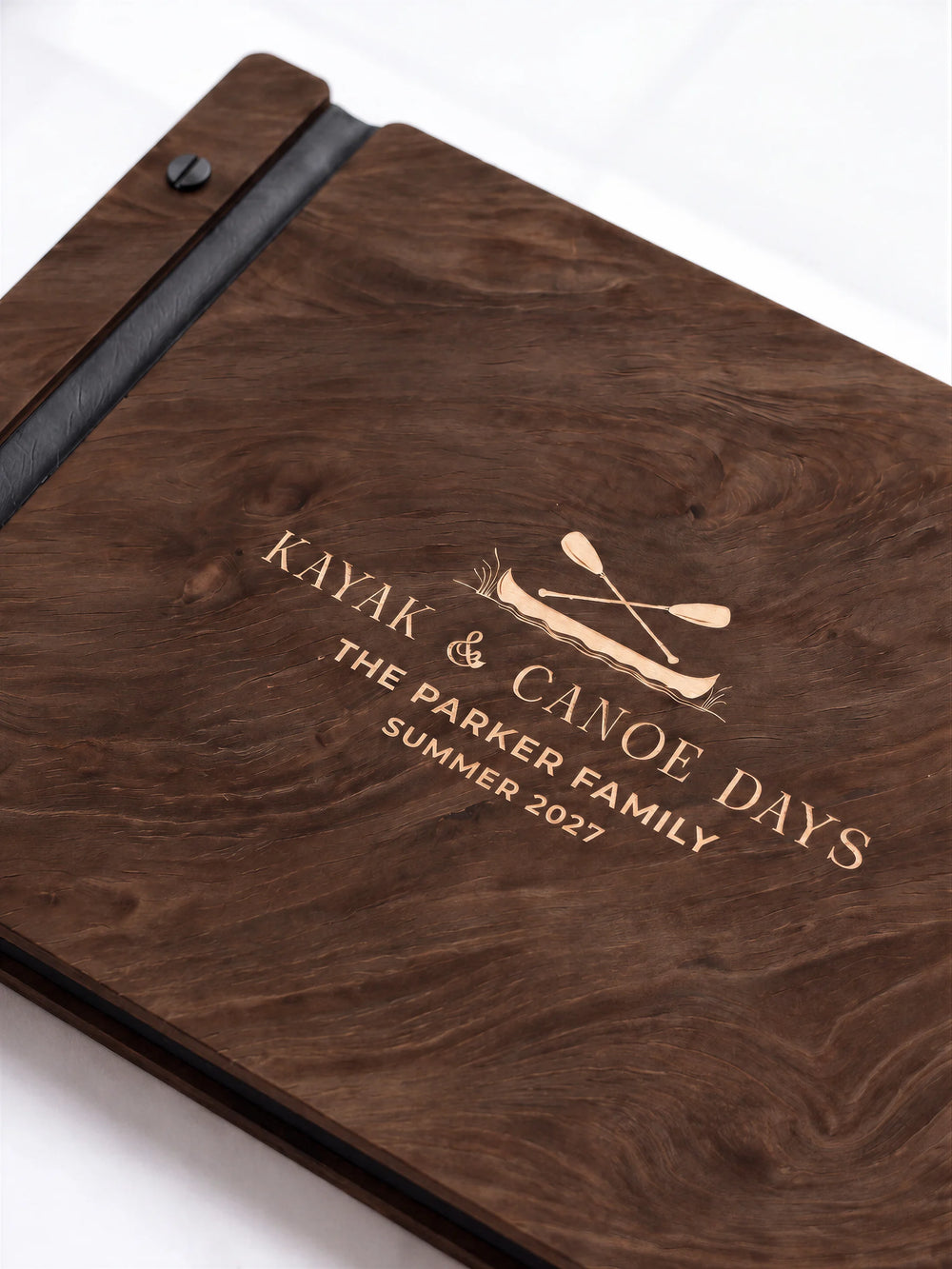 A close view of the dark brown Jacobean album and its cream laser-engraved KAYAK & CANOE DAYS design, with black binding and matte black screws.