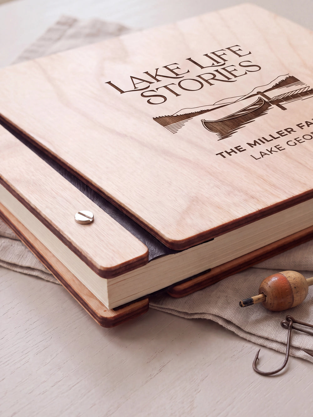 Close-up of the Natural wooden album binding: a polished silver slotted screw, black flexible hinge, separate wooden cover pieces and cream page edges.