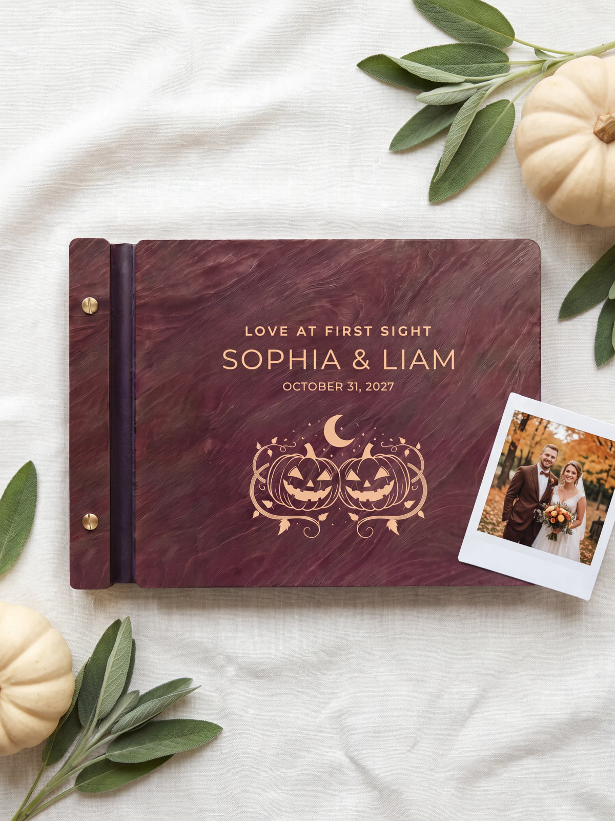 Jacobean wood Love at First Sight photo guest book lying flat on ivory linen, the cover engraved with “LOVE AT FIRST SIGHT”, “SOPHIA & LIAM” and “OCTOBER 31, 2027”; two gold-tone screws along the black vegan leather spine