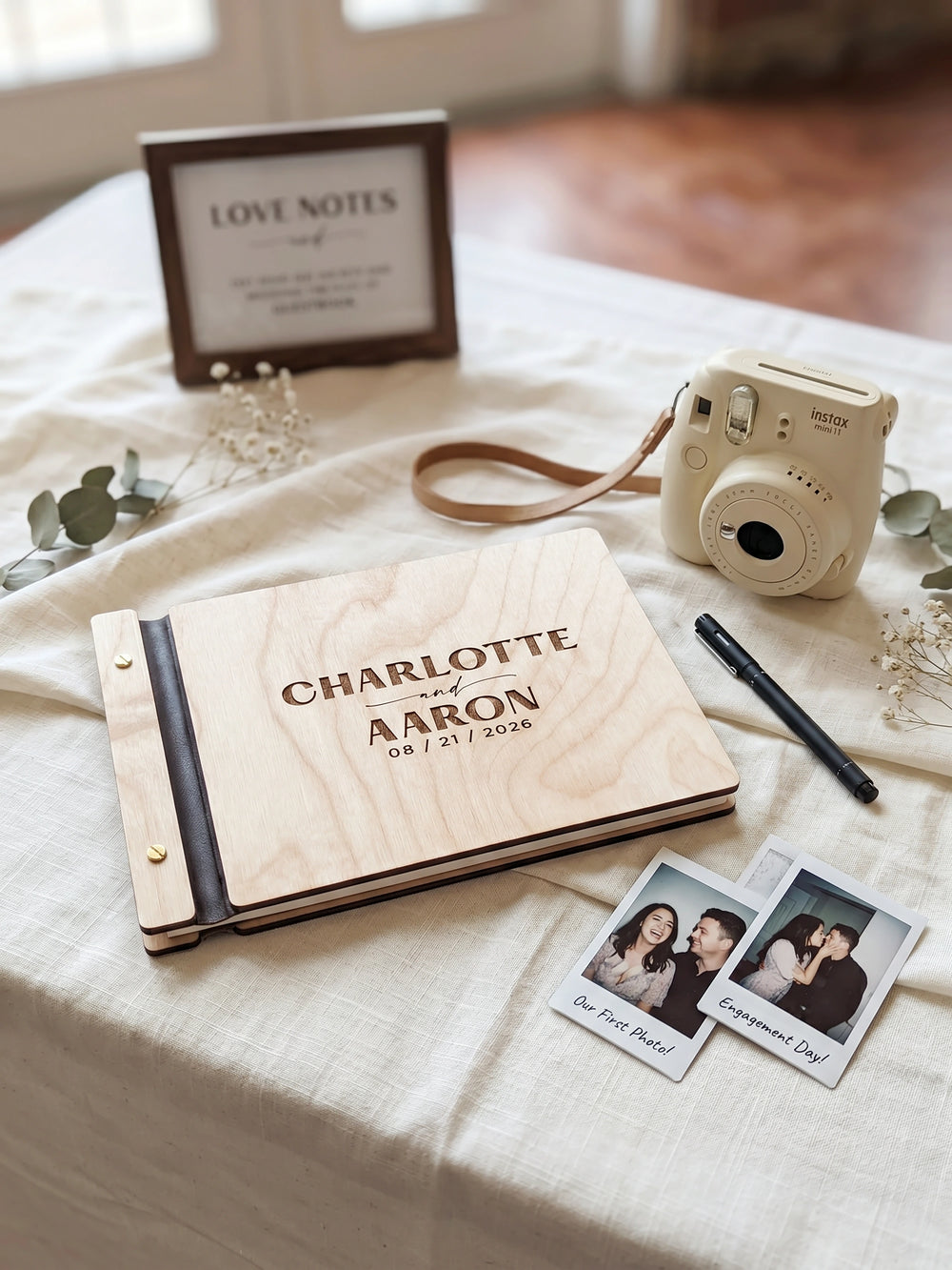 Jacobean wood Charlotte and Aaron photo guest book flat lay with dried roses, a cream ribbon, petals and instant photos