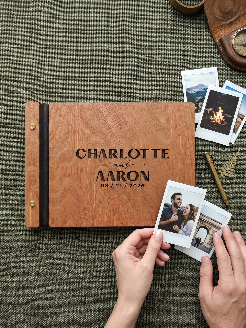 Jacobean wood Charlotte and Aaron photo guest book on an olive table runner with an instant camera, a pen and three instant photos