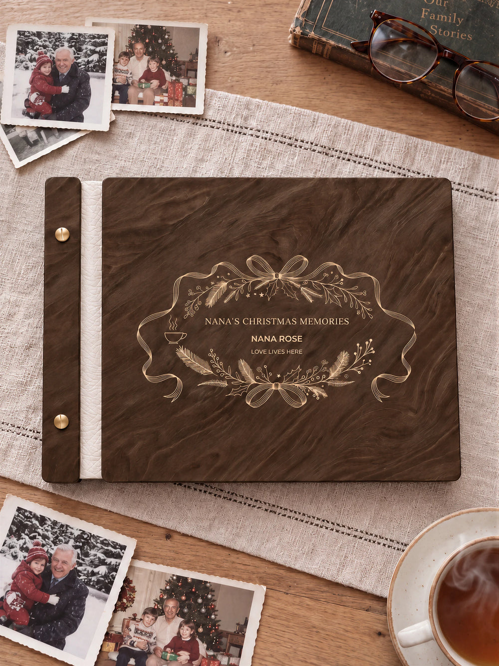 Jacobean wooden album with cream laser engraving of ribbon oval wreath, foliage and a small steaming cup. The full personalized cover rests on a styled surface, with ivory binding and gold screws.