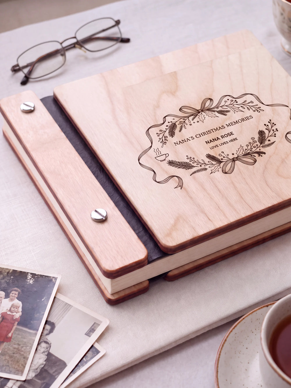 Close view of a Natural wood album with brown engraving, black binding and silver screw heads. The cream page edges and divided wooden cover construction are visible.