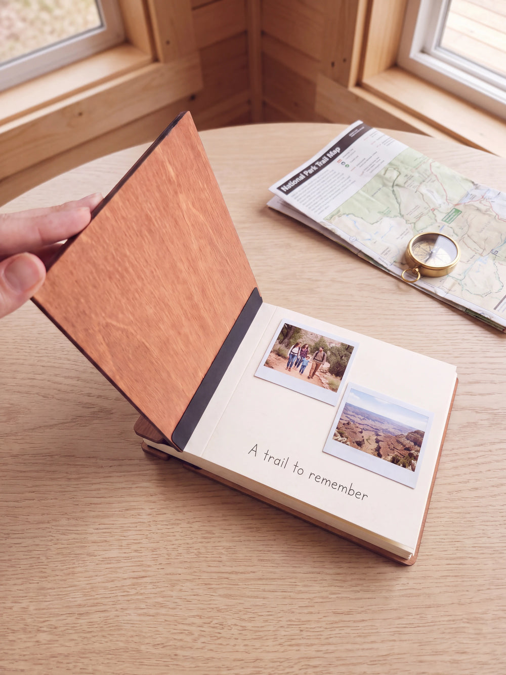 A hand lifts the Hazelnut album cover. Two family national park photos sit on a cream page above the handwritten note 