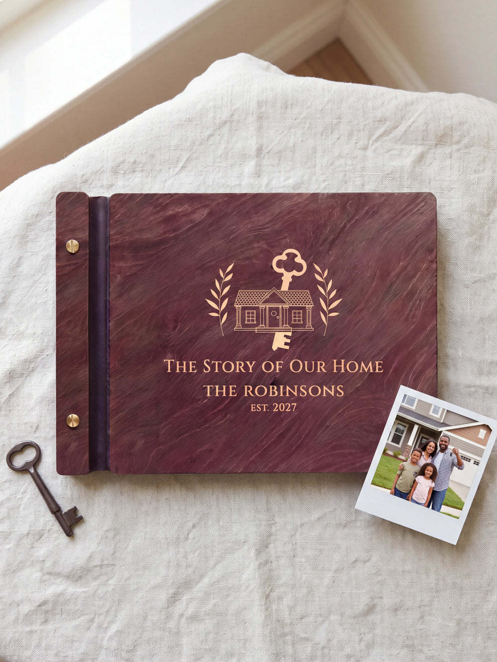 Jacobean wood The Story of Our Home photo book lying flat on natural linen, the cover engraved with “THE STORY OF OUR HOME”, “THE ROBINSONS” and “EST. 2027”; two gold-tone screws along the black vegan leather spine