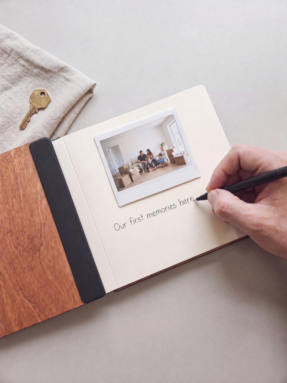 A hand writing a note in fine black pen beneath an instant photo on the cream page of the open Hazelnut The Story of Our Home photo book