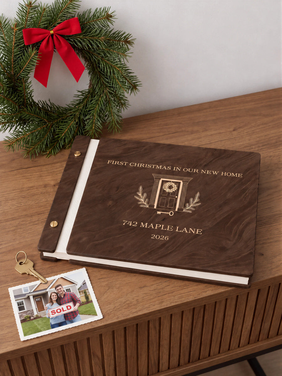 Jacobean wooden album with cream laser engraving of wreath-adorned front door and house key. The full personalized cover rests on a styled surface, with ivory binding and gold screws.