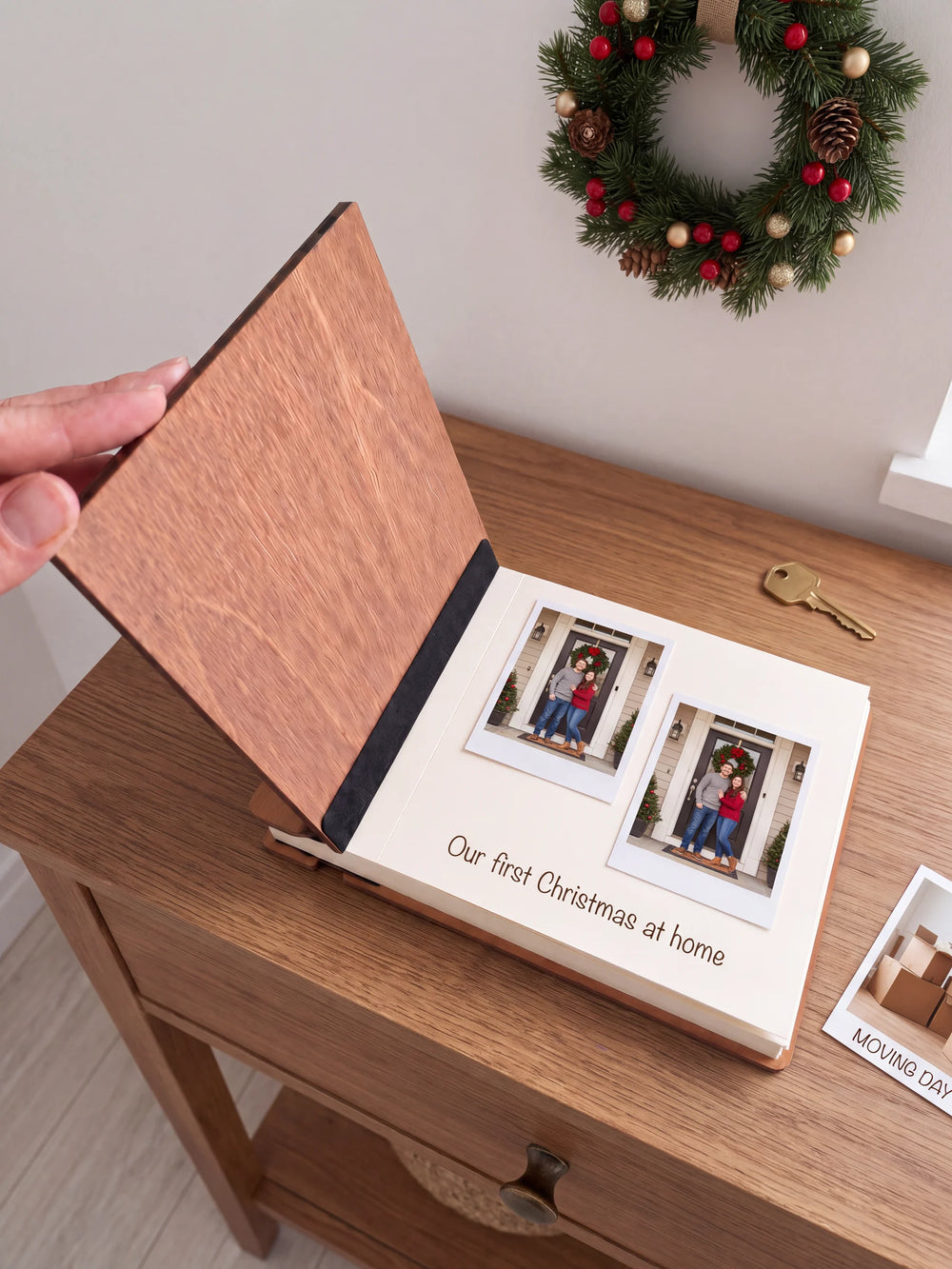 A hand lifts the Hazelnut album’s front cover, revealing a flat black inner fabric strip and a cream page arranged with instant photographs and a handwritten memory.