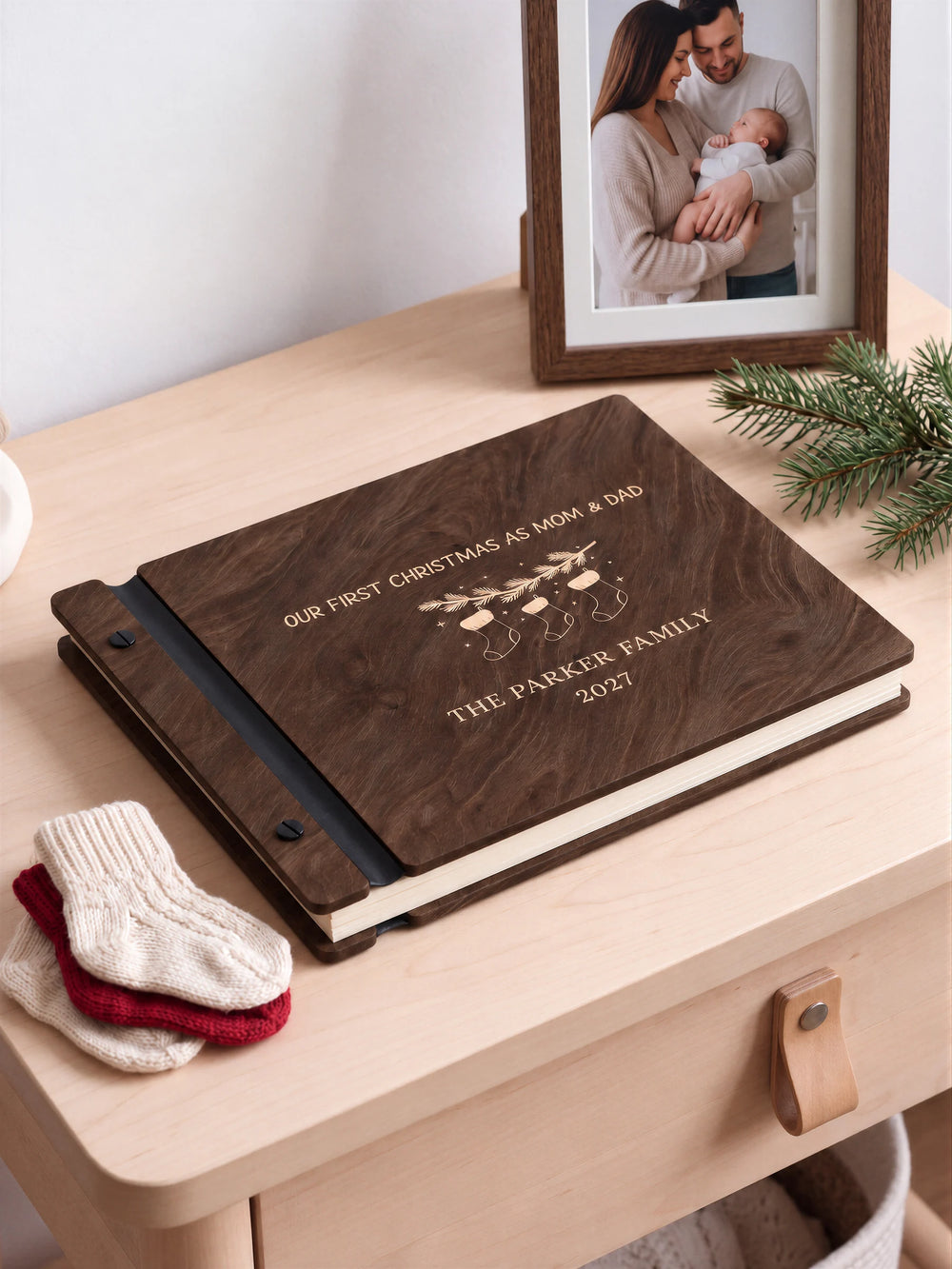 A close view of the dark brown Jacobean album and its cream laser-engraved Our First Christmas as Mom & Dad design, with black binding and matte black screws.