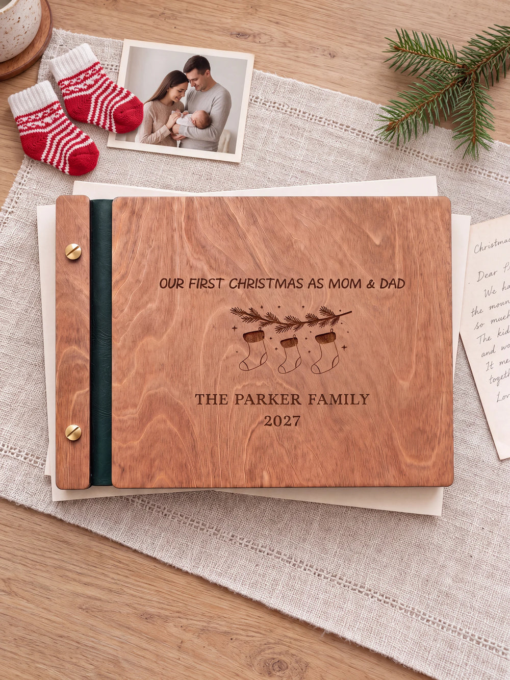 The full Hazelnut Our First Christmas as Mom & Dad album cover is shown close up. Brown engraved artwork, personalized wording, the narrow binding and gold screws are visible.
