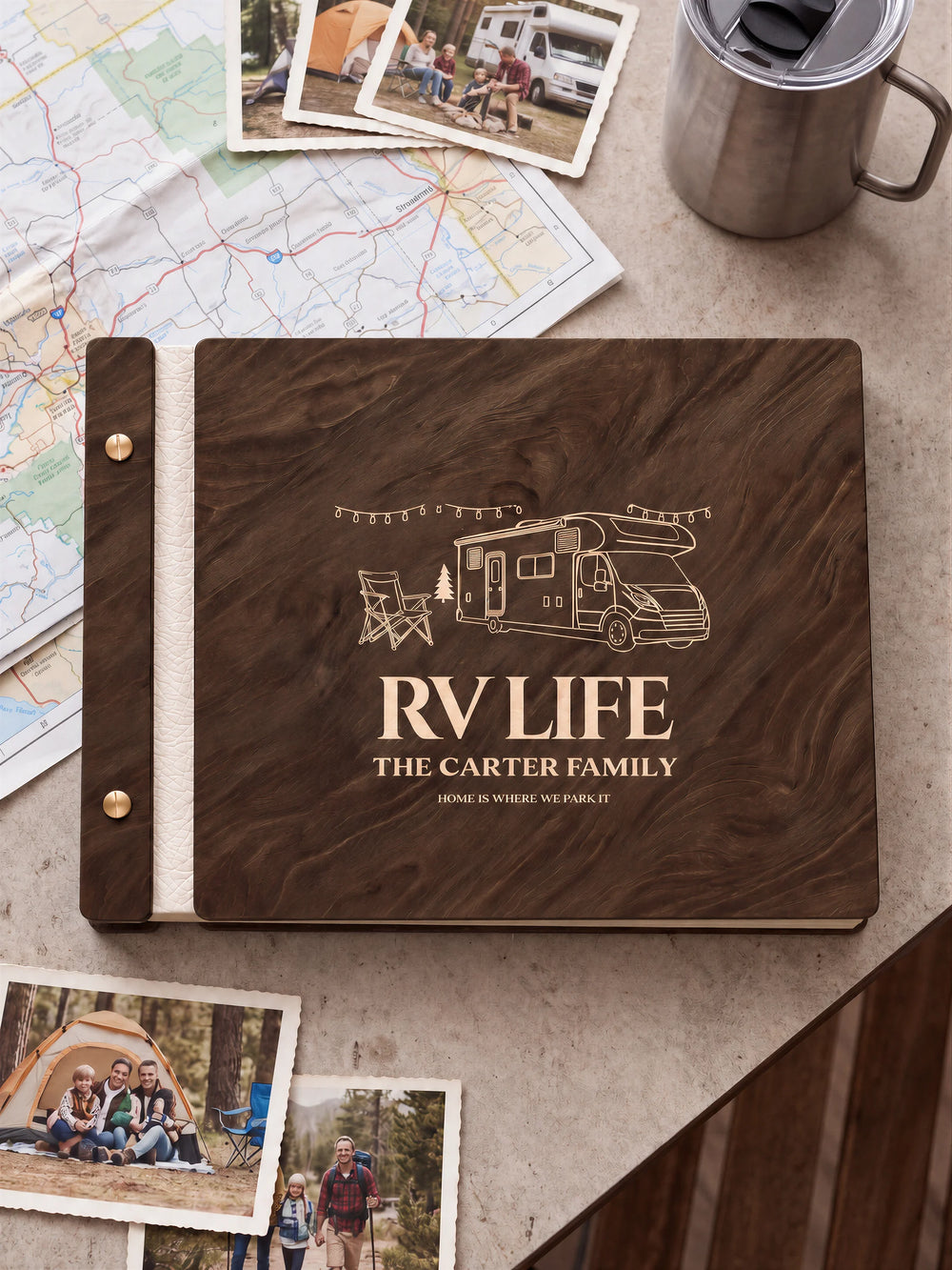 Jacobean wooden album with cream laser engraving of motorhome, camp chair and string lights. The full personalized cover rests on a styled surface, with ivory binding and gold screws.