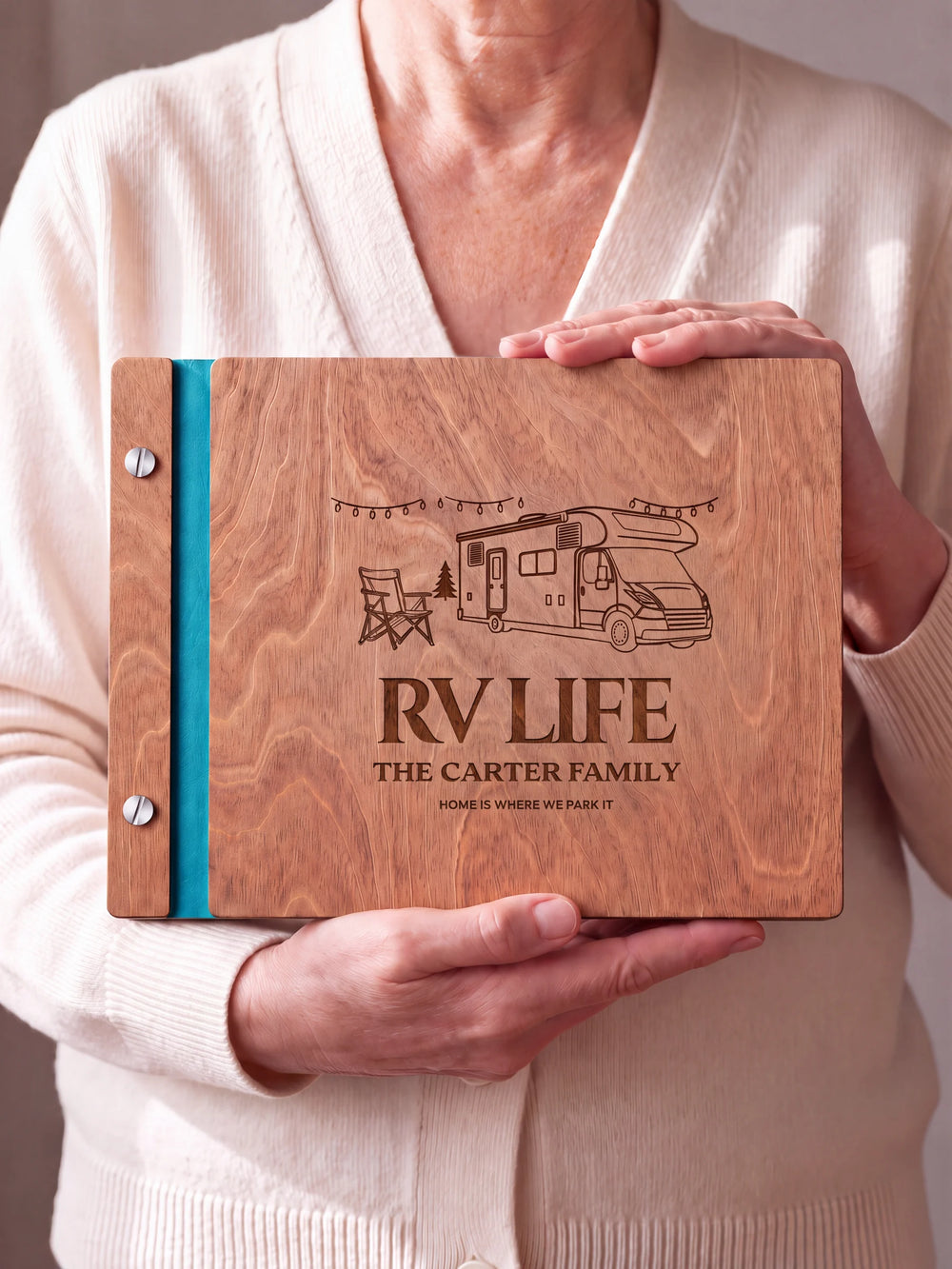 Two hands hold a Hazelnut wooden photo album. The RV LIFE cover design has brown engraving, turquoise binding and silver screws.