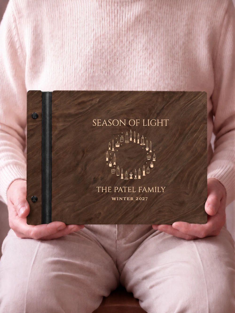 A close view of the dark brown Jacobean album and its cream laser-engraved SEASON OF LIGHT design, with black binding and matte black screws.