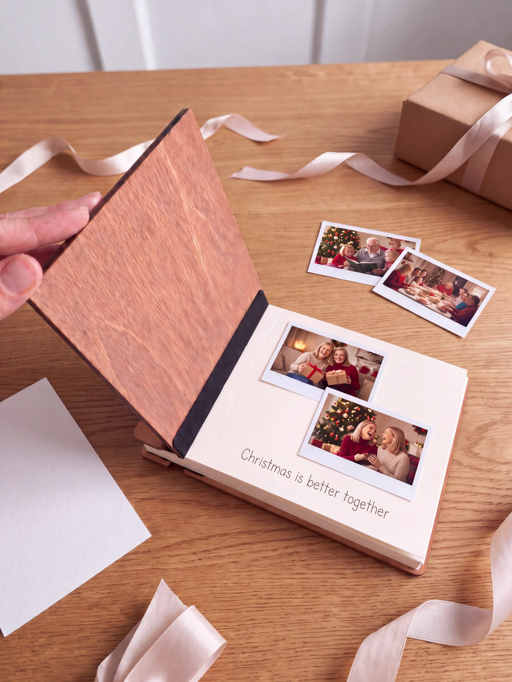A hand lifts the Hazelnut album’s front cover, revealing a flat black inner fabric strip and a cream page arranged with instant photographs and a handwritten memory.