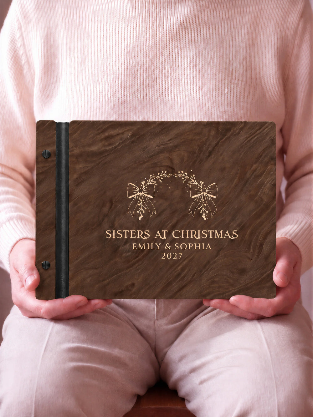 A close view of the dark brown Jacobean album and its cream laser-engraved SISTERS AT CHRISTMAS design, with black binding and matte black screws.