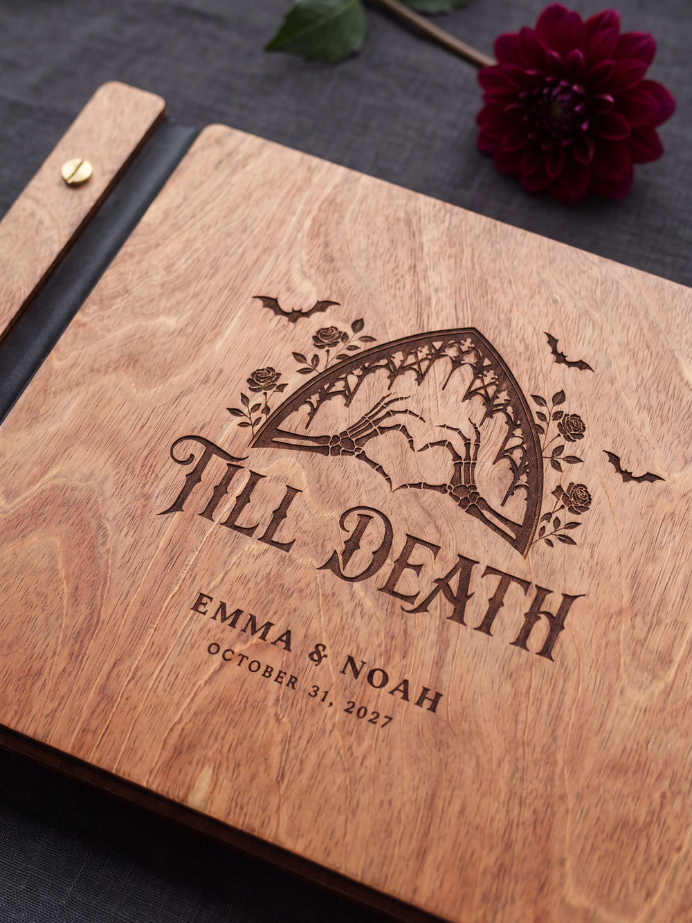Close-up of the laser engraving on Hazelnut wood: a gothic arch with skeleton hands forming a heart and the personalized text against the visible wood grain