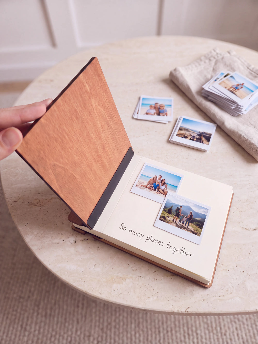 A hand lifts the Hazelnut album cover. Two family vacation photos sit on a cream page above the handwritten note 