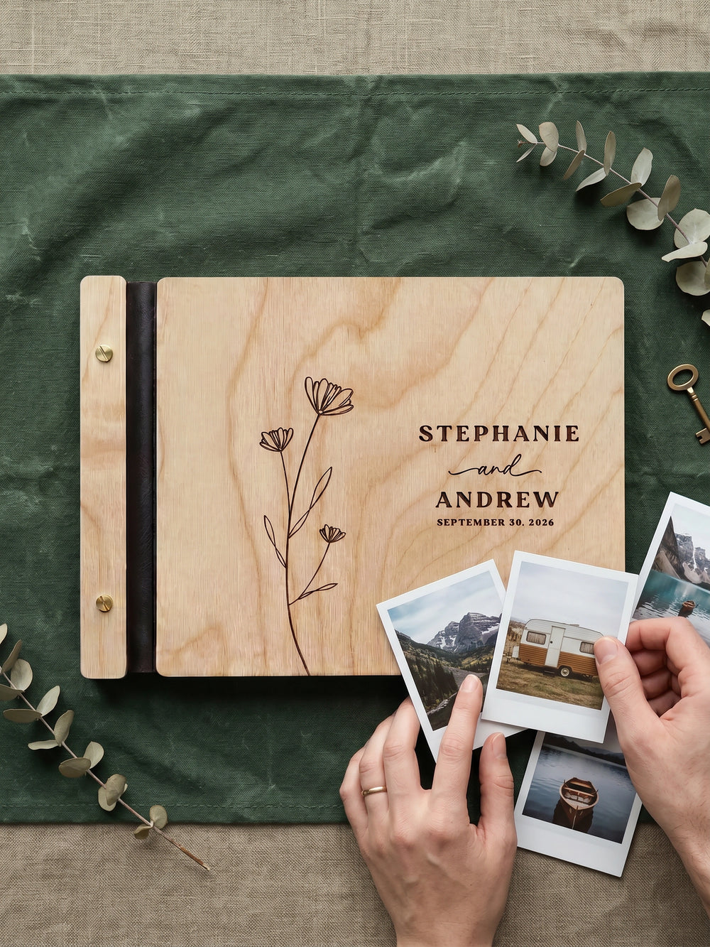 Natural wood wedding photo guest book engraved with a wildflower stem, Stephanie and Andrew, September 30, 2026, on green fabric with instant photos