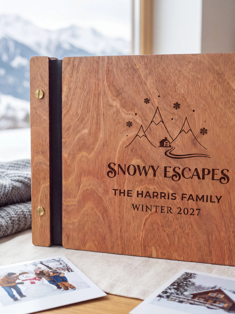 Close-up of snowy mountains, a cabin and snowflakes engraved in dark brown on the Hazelnut wooden cover, showing the fine artwork and surrounding wood grain.