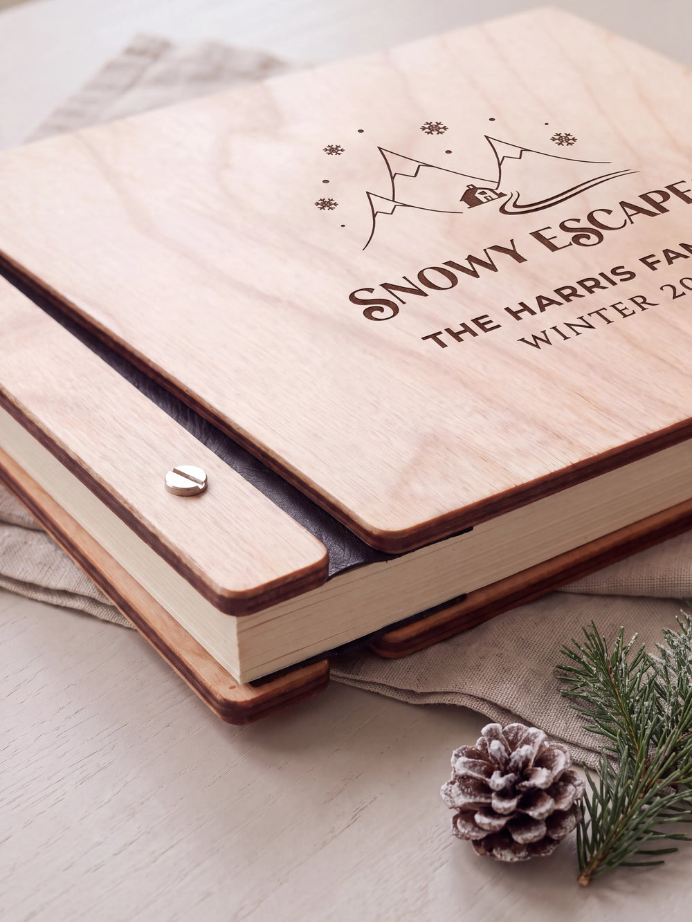 Close-up of the Natural wooden album binding: a polished silver slotted screw, black flexible hinge, separate wooden cover pieces and cream page edges.