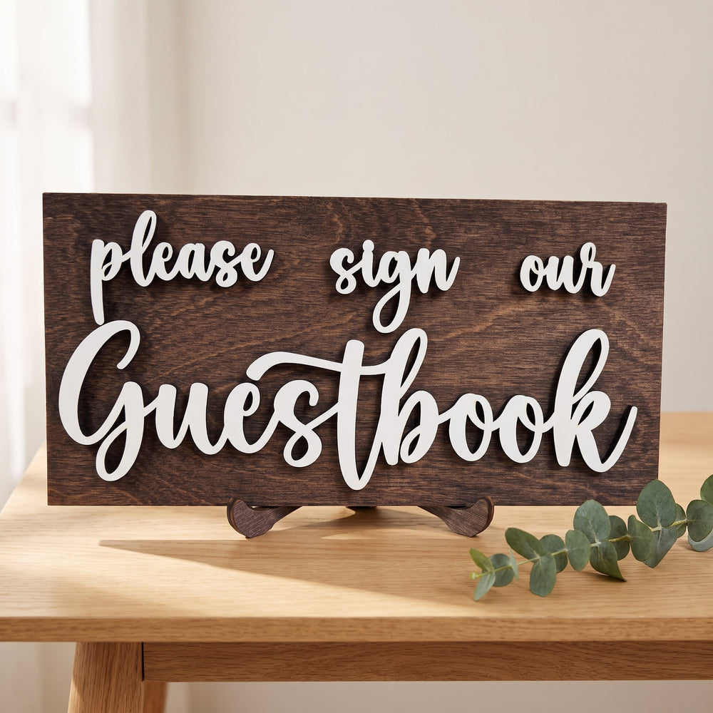 Please Sign Our Guestbook mini sign with raised white script letters on a dark stained wood board, on an oak table