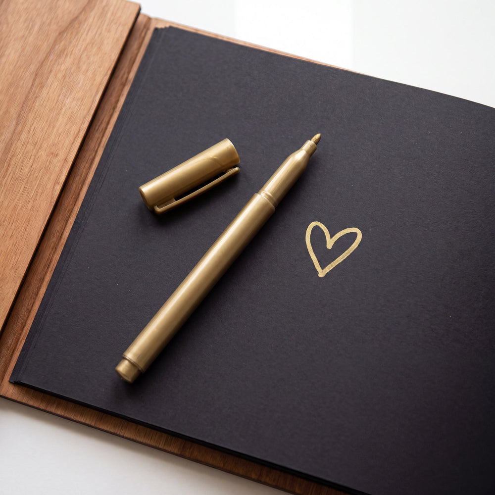 Gold signing marker with a small heart drawn on black cardstock